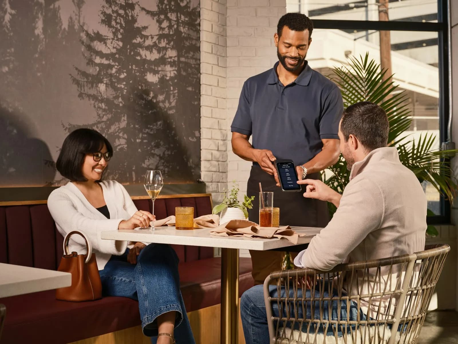Serveur qui montre l’écran de commande à un couple attablé