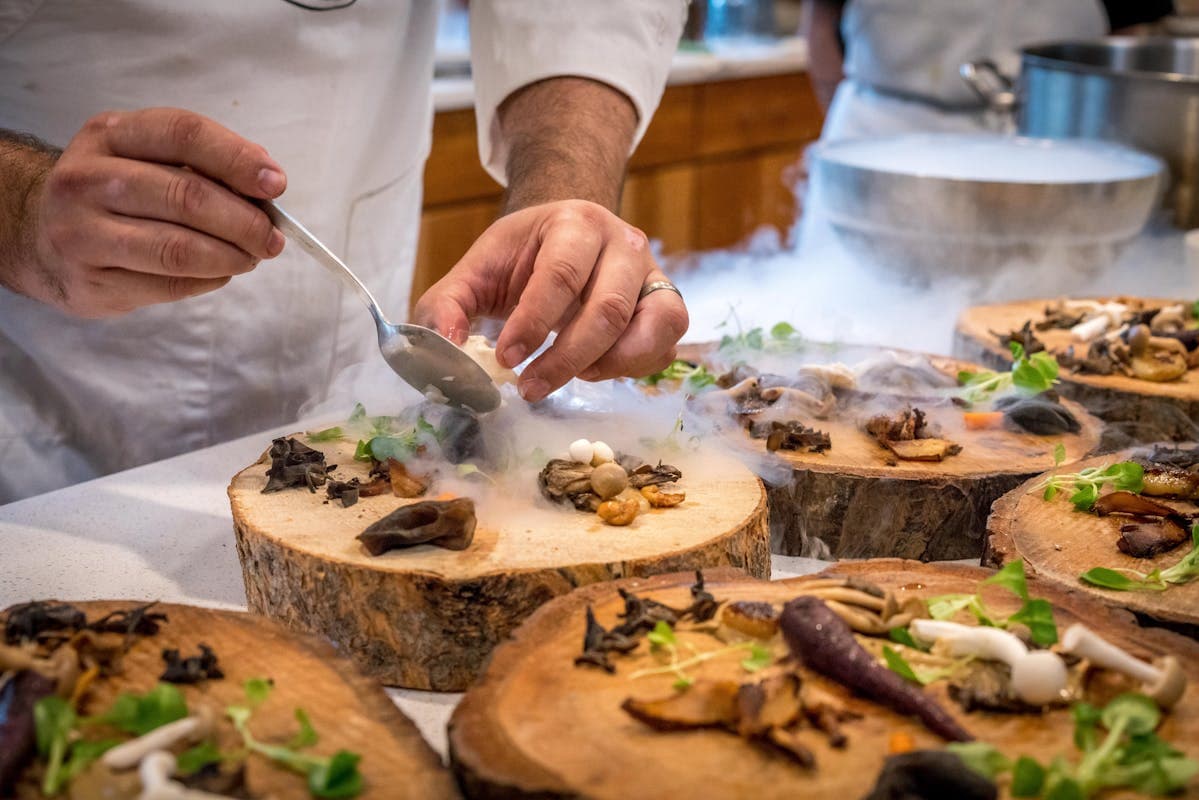 Mains d’un chef qui dressent une assiette