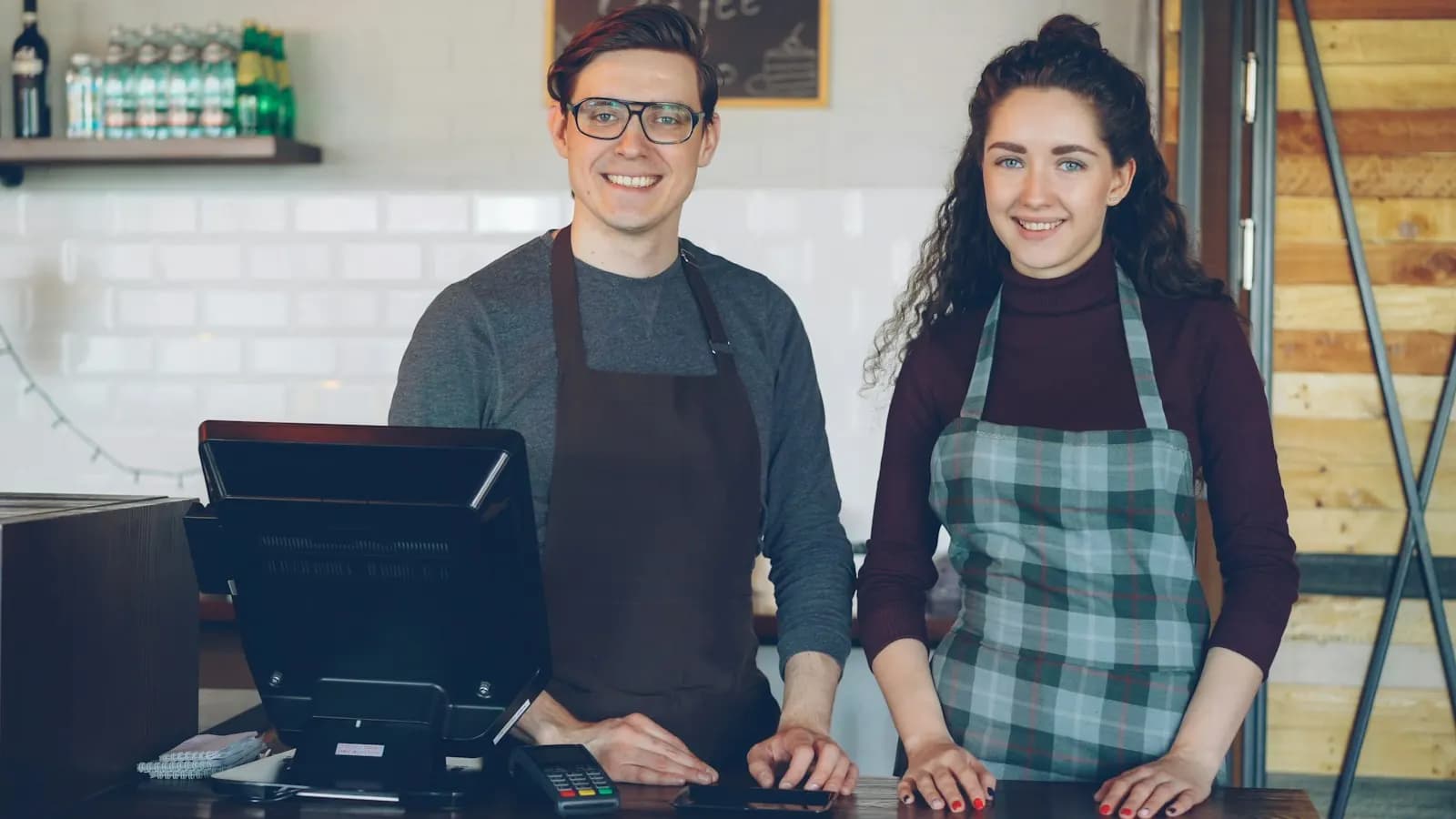 Deux employés souriants derrière le comptoir d’encaissement