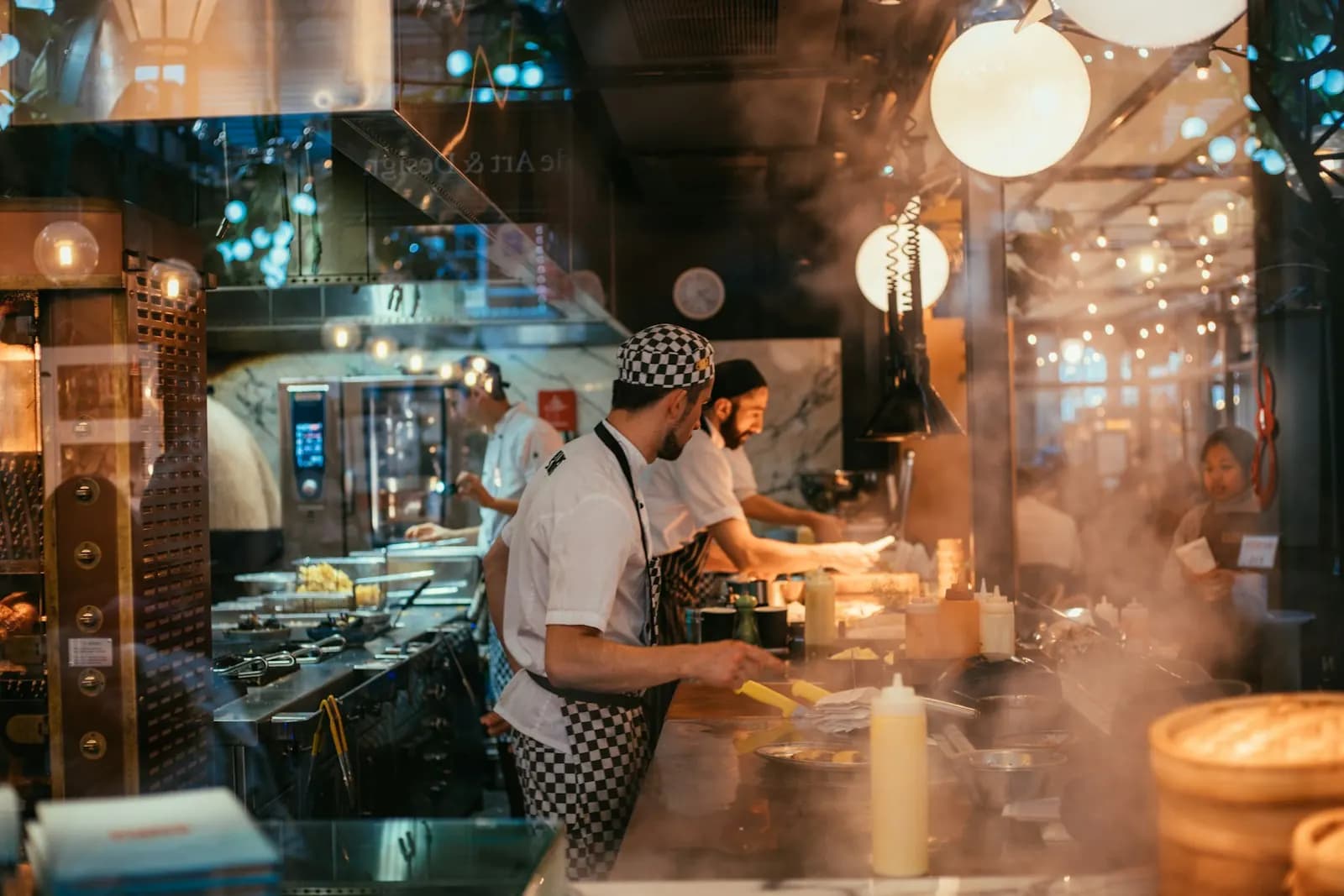 Cuisiniers en plein service derrière le passe d’une cuisine ouverte