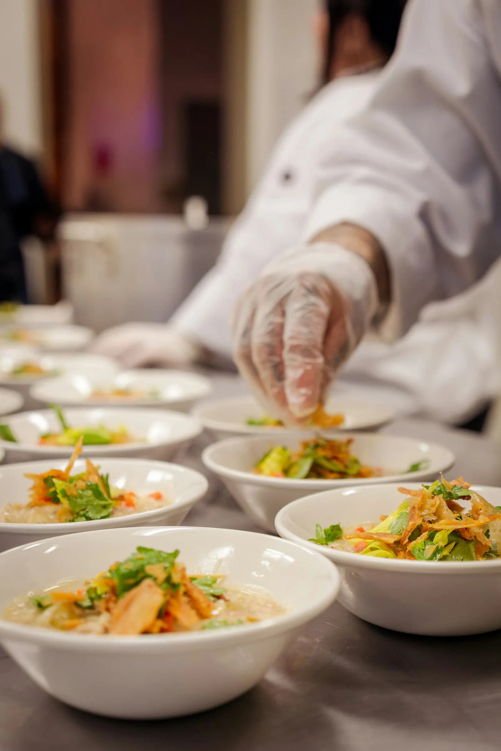 Chef en gants qui dresse une série de bols avant le service