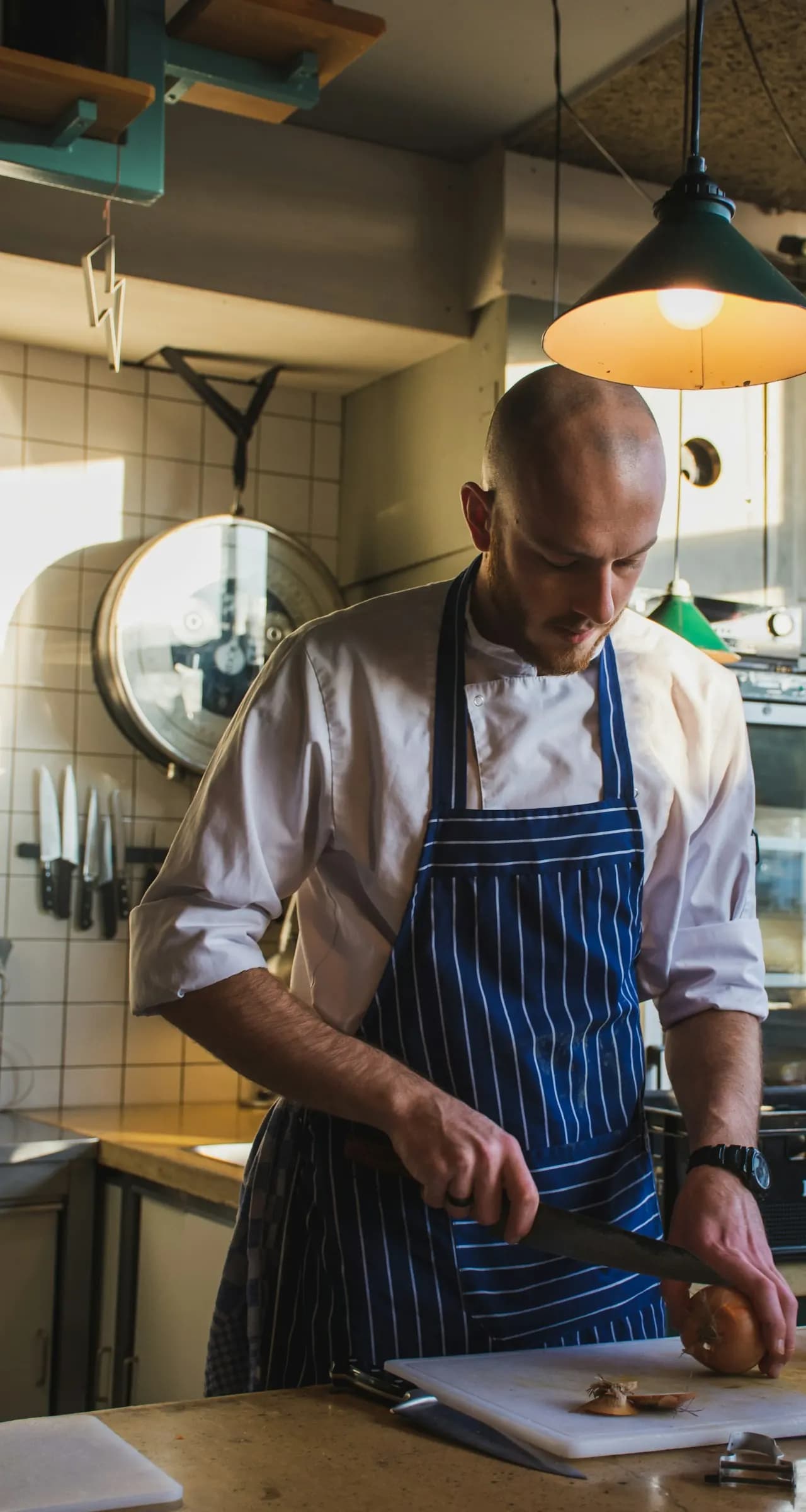 Cuisinier en tablier qui découpe sur sa planche pendant la mise en place