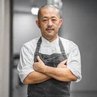 Chef en tablier, bras croisés, dans sa cuisine
